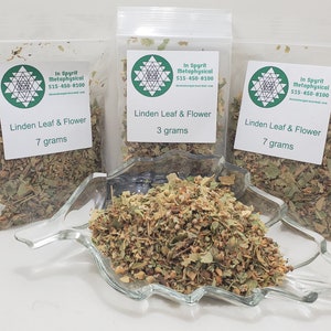 May include: Three clear plastic bags of Linden Leaf & Flower, with white labels indicating 7 grams and 3 grams. A clear glass dish contains loose Linden Leaf & Flower. The labels include the text "In Spyrit Metaphysical" and a phone number.