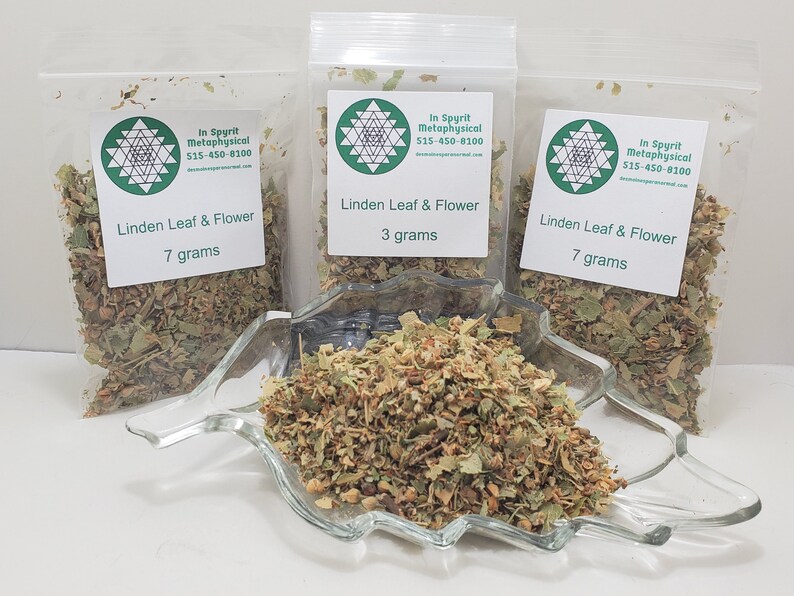 May include: Three clear plastic bags of Linden Leaf & Flower, with white labels indicating 7 grams and 3 grams. A clear glass dish contains loose Linden Leaf & Flower. The labels include the text "In Spyrit Metaphysical" and a phone number.