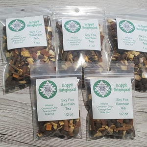 Puede incluir: Cinco bolsas de plástico transparente llenas de té Sky Fox Samhain. Cada bolsa tiene una etiqueta verde con el texto "In Spyrit Metaphysical" y los ingredientes del té. Las bolsas contienen una mezcla de hojas de té y especias marrones, naranjas y negras.