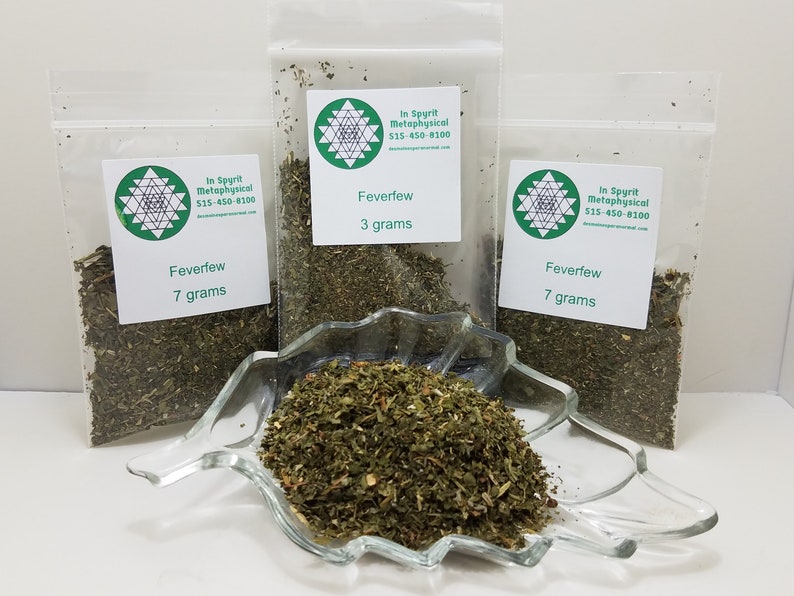 May include: Three clear plastic bags of Feverfew, labeled with the text "In Spyrit Metaphysical" and weights of 3 and 7 grams. A clear glass dish holds a pile of Feverfew. The product is displayed on a white surface.