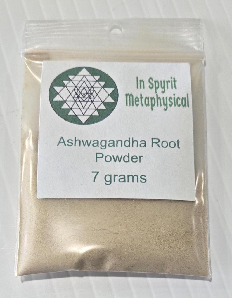 A clear bag containing 7 grams of Ashwagandha Root Powder from InSpyrit Metaphysical. The label features the sacred geometry logo and product details, showcasing the fine, tan-colored herbal powder used for grounding and vitality rituals.