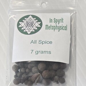 A small, clear plastic bag containing 7 grams of whole Allspice berries from InSpryitMetaphysical. The white label at the top displays the green and black shop logo, the product name "All Spice," and the "7 grams" weight. The dark brown, dried berries are visible through the transparent packaging against a light gray background.