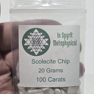 A close-up of a small, clear resealable bag filled with white Scolecite chip stones. The white label is clearly visible with the InSpyrit Metaphysical logo and the text "Scolecite Chip 20 Grams 100 Carats