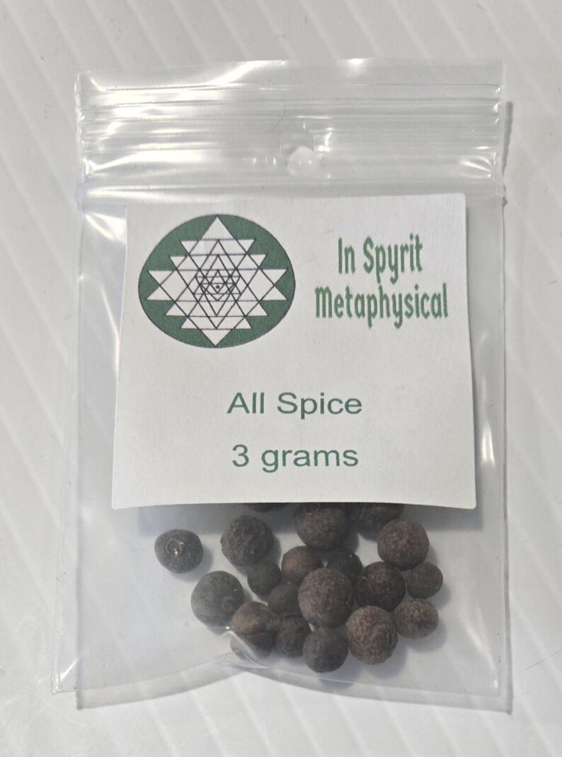 A small, clear plastic bag of whole Allspice berries from InSpryitMetaphysical. The white label features a green geometric logo at the top with the text "InSpryit Metaphysical," followed by "All Spice" and "3 grams." The dark brown, round dried berries are clustered at the bottom of the bag.