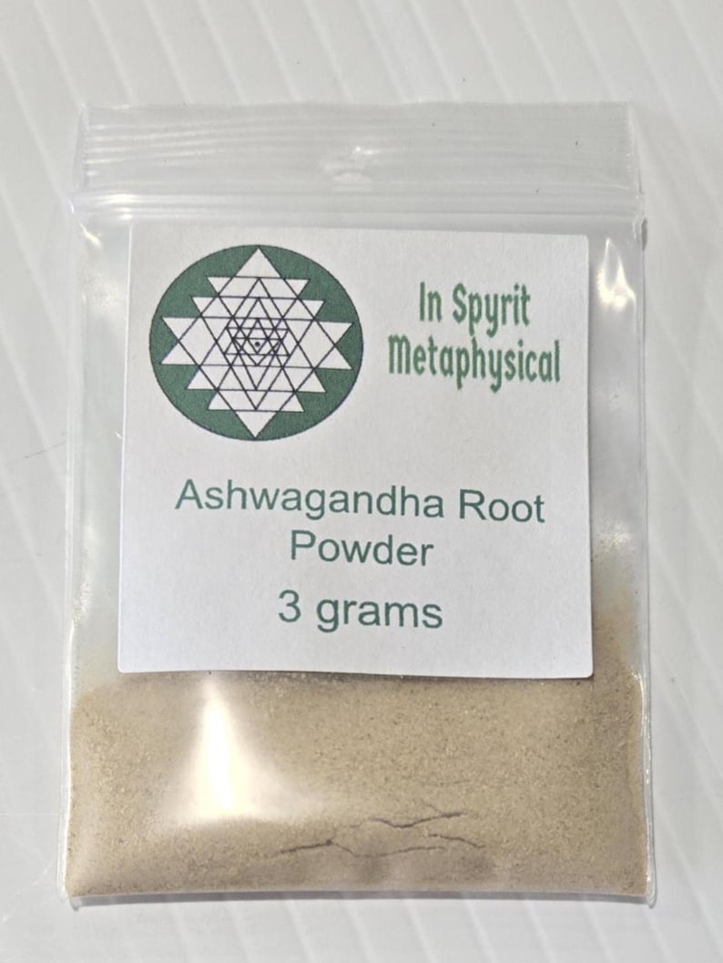 A small, clear bag containing 3 grams of finely ground Ashwagandha Root Powder from InSpyrit Metaphysical. The label features the sacred geometry logo and lists the botanical name Withania Somnifera, showcasing the fine, tan herbal texture.