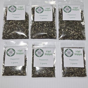 Könnte beinhalten: Sechs transparente Plastiktüten gefüllt mit getrockneten Pfefferminzblättern. Jede Tüte hat ein weißes Etikett mit dem Text "In Spyrit Metaphysical" und "Peppermint". Drei Tüten enthalten 7 Gramm, und drei enthalten 3 Gramm Pfefferminze.