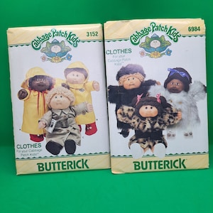 May include: Two vintage Cabbage Patch Kids sewing patterns. The pattern on the left is number 3152 and features a yellow raincoat, a brown trench coat, and a red jacket. The pattern on the right is number 6984 and features a black fur coat, a leopard print coat, and a white fur coat. Both patterns are from the brand Butterick.