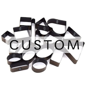 Puede incluir: Colección de herramientas de artesanía en cuero de varias formas, incluyendo cuadrados, círculos y triángulos. Las herramientas son marrones con interior blanco, dispuestas sobre un fondo blanco. La palabra "CUSTOM" está superpuesta en la imagen.