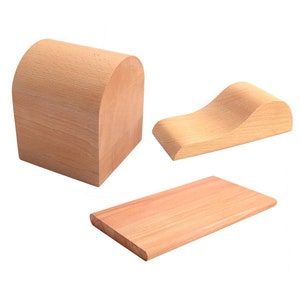 Può includere: Tre blocchi di legno artigianali di forme diverse. Uno è un blocco rettangolare curvo, un altro è una forma curva a forma di onda, e il terzo è un blocco rettangolare piatto. Tutti sono in legno chiaro.