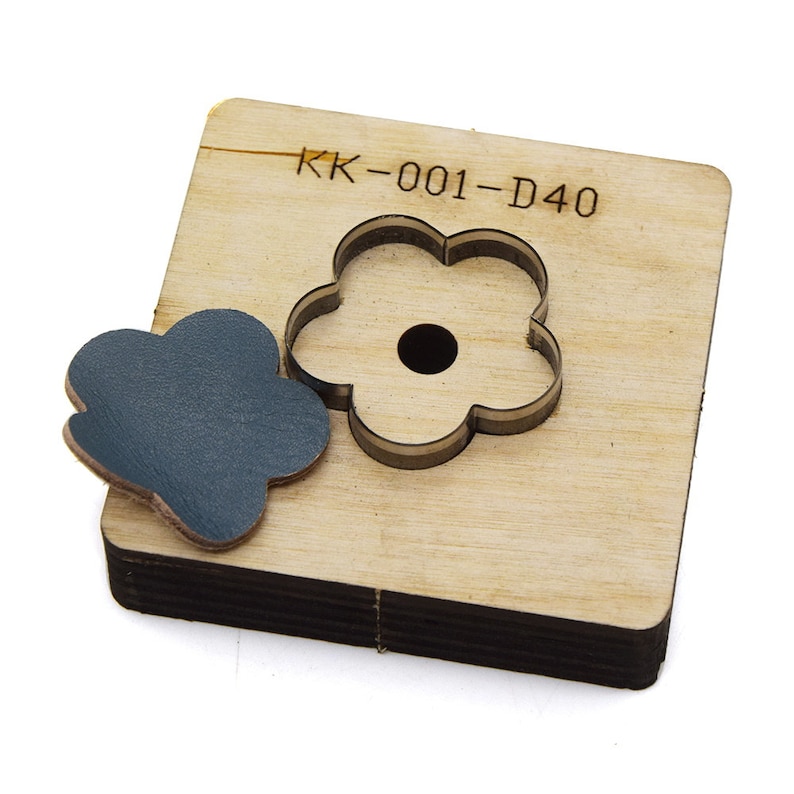 May include: A wooden die-cut tool with a flower-shaped cutout and a matching leather piece. The tool has the text "KK-001-D40" printed on it. The leather piece is dark blue.