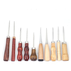 May include: A collection of ten awls with wooden handles and metal tips. The handles vary in shape and color, ranging from dark brown to light wood. These tools are designed for piercing and marking materials.