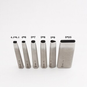 May include: A collection of six silver leathercraft tools, each with a different rectangular or oval cutting head. The tools are marked with sizes like 4*6 and 5*25. They are displayed vertically against a plain white backdrop.