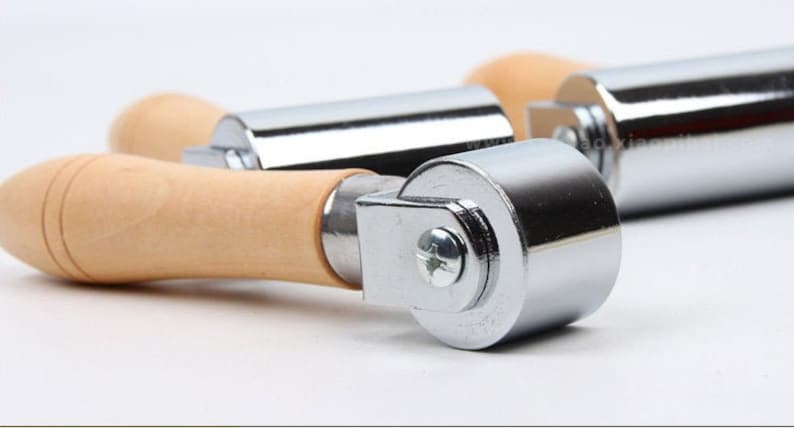 Peut inclure: Gros plan sur trois rouleaux &agrave; main en m&eacute;tal et en bois. Les rouleaux ont un corps cylindrique en m&eacute;tal et une poign&eacute;e en bois. Les parties m&eacute;talliques sont brillantes et r&eacute;fl&eacute;chissantes, et le bois est de couleur brun clair.