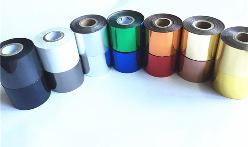 May include: An assortment of foil rolls in various colours, including black, silver, white, blue, green, copper, red, and gold. The rolls are stacked, displaying their shiny, reflective surfaces. The image is well-lit, highlighting the range of colours and textures.