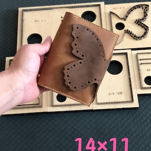 May include: A brown leather wallet with a butterfly design, held in a hand. The butterfly is a darker shade of brown and has decorative cut-out holes. The wallet is approximately 5.5 inches by 4.3 inches. Wooden crafting templates are in the background.