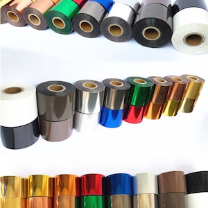 May include: A selection of metallic foil rolls in a range of colours, such as gold, silver, red, green, blue, and black. The rolls are stacked and arranged in rows, displaying the variety of colours and finishes.