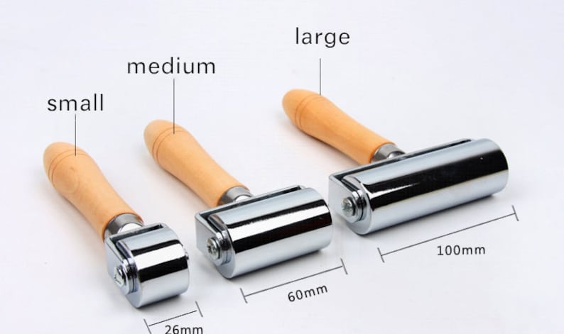 Peut inclure: Trois rouleaux &agrave; main en m&eacute;tal avec des manches en bois, &eacute;tiquet&eacute;s petit, moyen et grand. Le grand rouleau mesure 10 cm de long, le moyen 6 cm et le petit 2,6 cm. Les rouleaux sont argent&eacute;s et les manches sont brun clair.