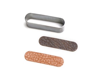 May include: A silver-colored metal oval loop frame positioned above two rectangular strips with rounded ends. One strip is dark brown with a textured surface, and the other is a lighter tan color with a matching textured surface finish.