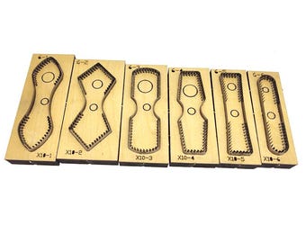 May include: A collection of six wooden die-cut tools with various shapes. Each tool has a metal cutting edge and is mounted on a rectangular wooden base. The tools are labeled with numbers and letters, and are arranged in a row against a white background.
