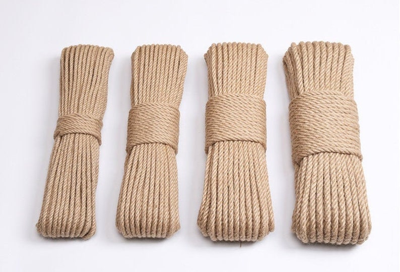 May include: Four bundles of natural-colored rope, tightly wound and secured with matching rope. The bundles are arranged side by side against a white background. The rope appears to be made of a coarse, fibrous material.