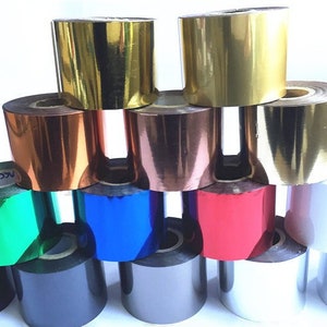May include: A collection of foil rolls in a range of colours, such as gold, copper, blue, and red. The rolls are tightly wound and have a shiny, metallic finish. The image is well-lit, highlighting the different colours and textures of the foil.