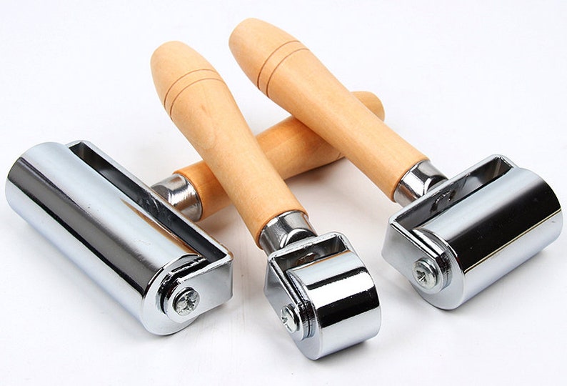 Peut inclure: Trois rouleaux &agrave; joints chrom&eacute;s avec des manches en bois. Les rouleaux sont cylindriques et con&ccedil;us pour lisser les surfaces. Les manches sont en bois clair et de forme ergonomique pour une prise en main confortable.