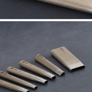 May include: A collection of silver metal leather working tools. One tool is marked with "Bangbang 5*25". The tools have rounded ends and are displayed on a dark grey surface. The tools are used for leathercraft.