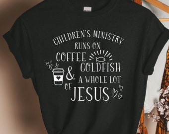 May include: Black t-shirt with white text that reads "Children's Ministry runs on coffee & goldfish & a whole lot of Jesus." The design includes a coffee cup, hearts, and a fish.