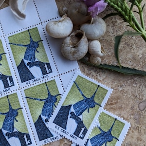 May include: A sheet of vintage US postage stamps featuring a snail wearing a tuxedo and bow tie. The stamps are green and yellow with the text "U.S. Snail Mail" and "1c".