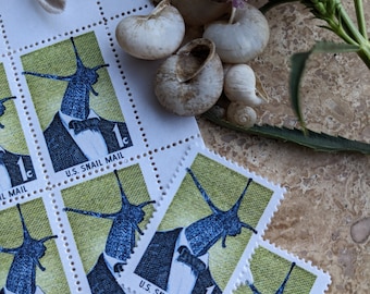 Könnte beinhalten: Eine Blatt mit alten US-Briefmarken, auf denen eine Schnecke in Smoking und Fliege zu sehen ist. Die Briefmarken sind grün und gelb mit dem Text "U.S. Snail Mail" und "1c".