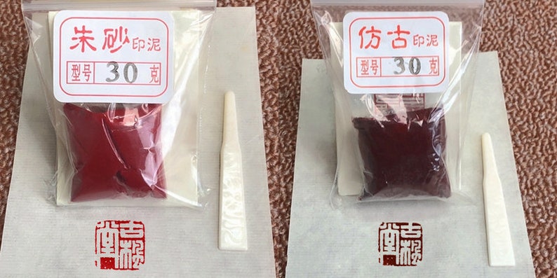 May include: Two small plastic bags containing red and burgundy colored paint with a small wooden applicator. The bags are labeled with the text "末  刷" and "30  克" and "仿古" and "30  克".
