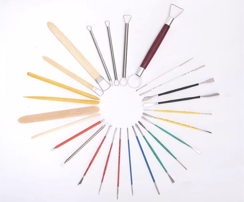May include: A set of 20 pottery tools, including wooden and metal sculpting tools. The tools are arranged in a circle on a white background.