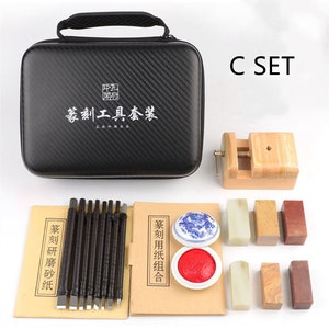 May include: A black carrying case with a Chinese inscription, a set of carving tools, a wooden clamp, and a set of red and green ink pads and stamps. The set is labeled "C SET".