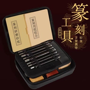 May include: A black carrying case with a zippered closure, containing a set of carving tools, two books with Chinese text, and a small wooden block. The case has a label that reads "Beginner's Guide" in Chinese. The text on the books reads "Carving Research and Practice" and "Carving Application and Combination".