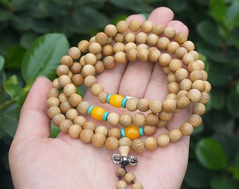 May include: A wooden prayer bead necklace with yellow and turquoise accents. The necklace is made of small, round beads and has a silver charm at the end.