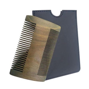 May include: A wooden comb with a black leather case. The comb has a curved shape and fine teeth. The case has a flap that closes with a snap.