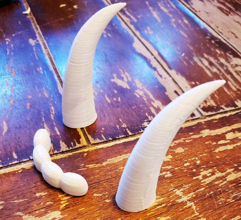 May include: Three white plastic horns, two are long and curved, one is shorter and curved in a U-shape.
