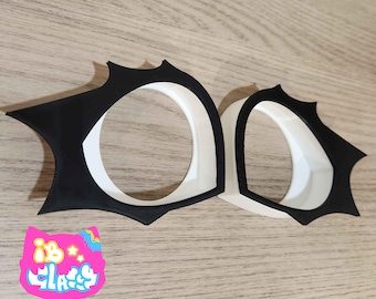 May include: Two black and white plastic eye masks with a jagged edge design. The masks have a white inner circle and a black outer edge.