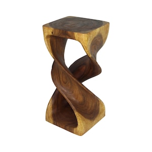 May include: A tall, square-topped wooden stool featuring a continuous, spiraling, twisted central column. The piece is crafted from natural wood with visible grain patterns in varying shades of dark brown, tan, and light golden yellow throughout.