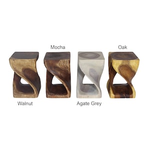May include: Four wooden stools in different colors: Walnut, Mocha, Agate Grey, and Oak. Each stool has a square top and a twisted, open base. The names of the colors are printed below each stool.
