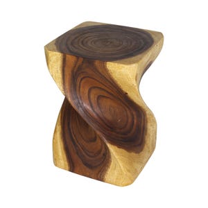 May include: A solid wood stool featuring a distinct twisted hourglass shape. The piece displays a natural grain pattern with contrasting dark brown heartwood at the center and lighter tan sapwood along the edges, creating a smooth, polished finish.