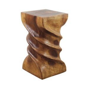 May include: A solid brown wooden stool featuring a distinct spiral or twisted design carved into the central column. The piece has a square top and a square base, showcasing the natural grain patterns and warm tones of the wood throughout.