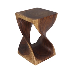 May include: A dark brown wooden stool featuring a square top and base connected by a central twisted, hourglass-shaped support. The piece displays a natural wood grain pattern with smooth, curved edges throughout its solid construction.