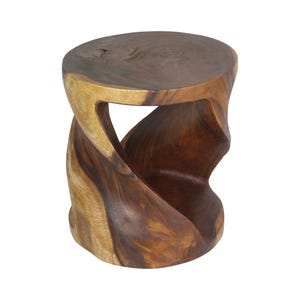 May include: A round stool carved from a single piece of dark and light brown wood. The base features a twisted, hourglass-like silhouette with a smooth, polished surface that highlights the natural grain patterns and variations in the wood color.