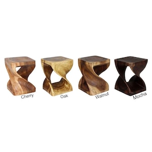 May include: Four wooden stools in different wood stains: cherry, oak, walnut, and mocha. Each stool has a unique twisted design.