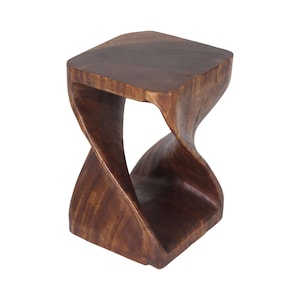 May include: A dark brown wooden stool featuring a square top and a base connected by a central twisted, hourglass-shaped support structure. The piece has a smooth, polished finish that highlights the natural grain patterns of the wood throughout.