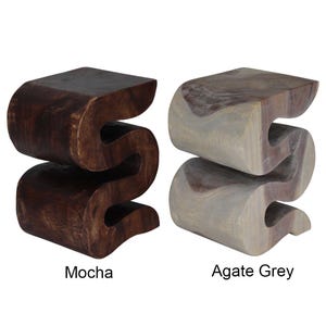 May include: Two wooden stools in the shape of an 'S' with a wavy design. The stool on the left is a dark brown color labeled 'Mocha'. The stool on the right is a light gray color labeled 'Agate Grey'.