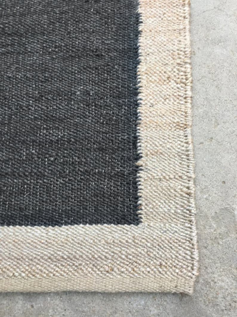 May include: A black and white rug with a woven texture. The rug has a black center and a white border.