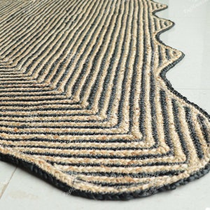 May include: A black and natural jute rug with a wavy edge and a chevron pattern.