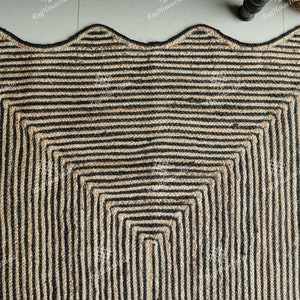 May include: A black and natural jute rug with a wavy edge and a geometric pattern of black stripes. The rug is made of natural fibers and has a rustic look.